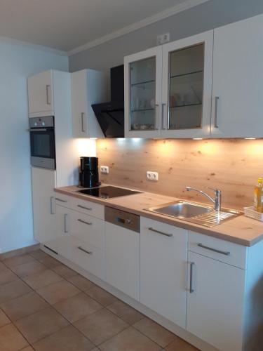 a kitchen with white cabinets and a sink at Wellnessresidenz "Klaus Störtebeker" App6 in Zingst
