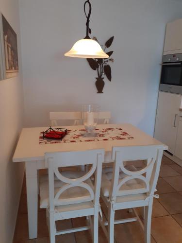 a kitchen with a white table with chairs and a light at Wellnessresidenz "Klaus Störtebeker" App6 in Zingst