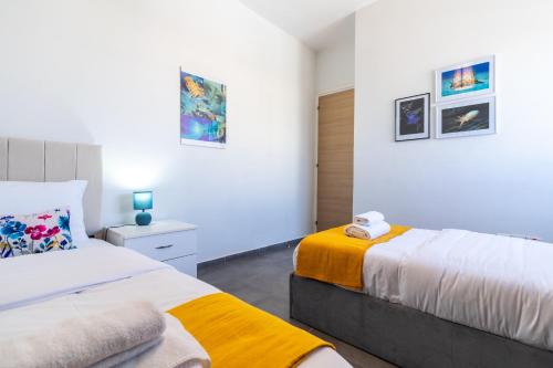two beds in a bedroom with white walls at Snobby 2-Bedroom Apartment in Larnaca