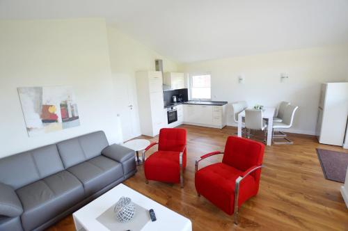 a living room with a couch and two red chairs at Gartenhaus 2, inkl 1 Parkplatz in Fehmarn