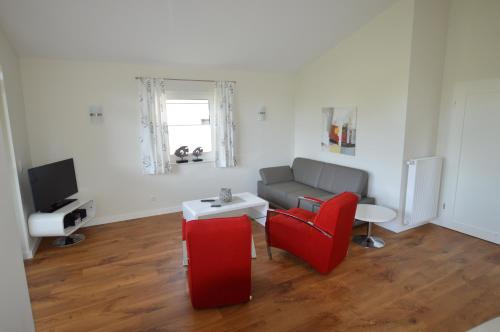 a living room with a couch and a red chair at Gartenhaus 2, inkl 1 Parkplatz in Fehmarn