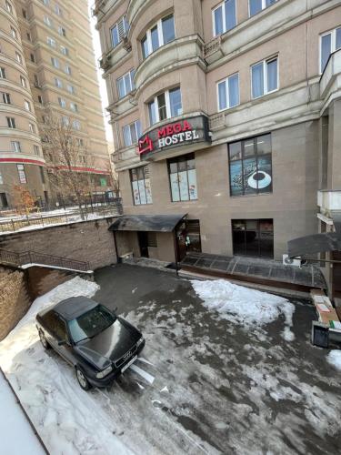 a car parked in a parking lot in front of a hotel at Mega Hostel in Almaty