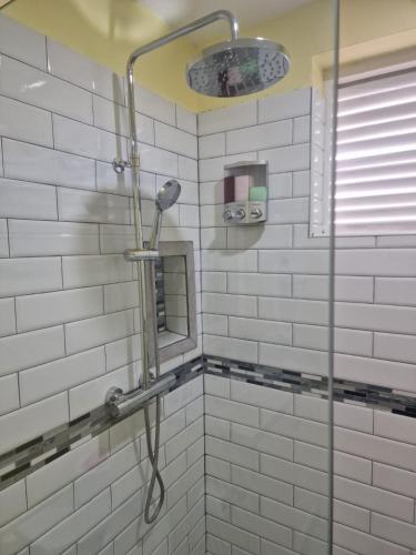 a shower in a bathroom with white tiles at Amazon Villas- Hummingbird in Soufrière