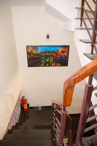 a staircase with a painting hanging on the wall at Gold Stone Hoi An Homestay in Hoi An