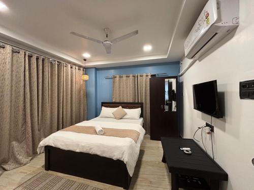 une chambre avec un lit et une télévision au mur dans l'établissement Lily Homes, à Guwahati