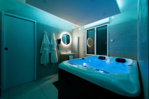 a blue bathroom with a tub with a window at Escapade Relaxante - Spa - Jacuzzi - Sauna - Privés in LʼIsle-Adam