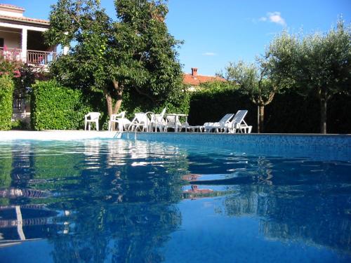 a swimming pool with white chairs and blue water at Ferienhaus - Bungalow Lavanda 4 in Poreč