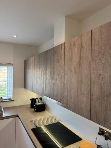 a kitchen with wooden cabinets and a counter top at Three-bedroom modern family home by the pond with free parking in Warfield