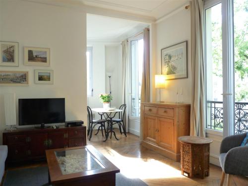 un salon avec une télévision et une table dans l'établissement Le Alesia, à Paris