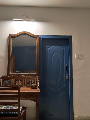 a blue door next to a table and a mirror at Nama-Stay - An escape villa in Ooty