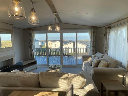 a living room with two couches and a balcony at Stunning Lodge with sea and country views, sleeps 6 in Newquay
