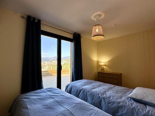 - une chambre avec 2 lits et une fenêtre avec vue dans l'établissement Superbe vue Mer et Montagne - T3 - 5mn des plages, à Propriano