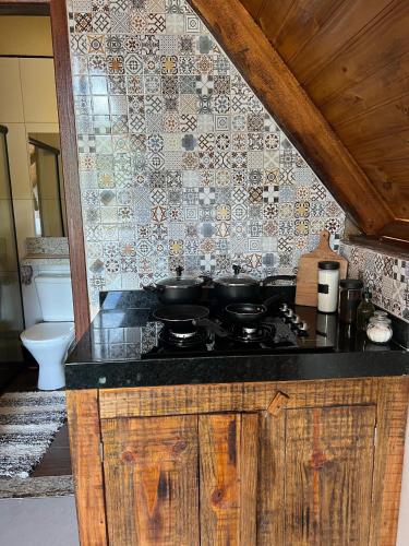 a kitchen with a stove and a tile wall at CHALÉS VILA RICA - Bar do Ricardo in Ouro Preto