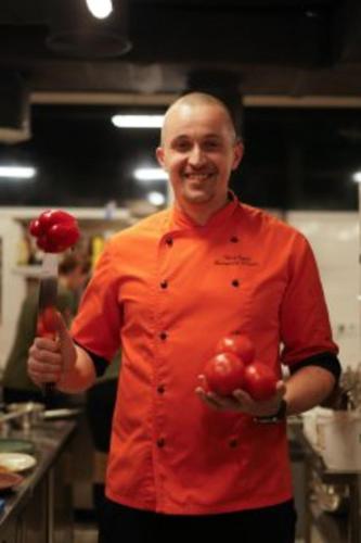 a man in a kitchen holding a bunch of tomatoes at Stara Pravda Hotel in Bukovel