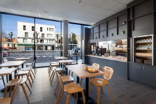 un restaurant avec des tables et des chaises et une vue sur une rue dans l'établissement B&B HOTEL Bordeaux Centre Bègles, à Bègles