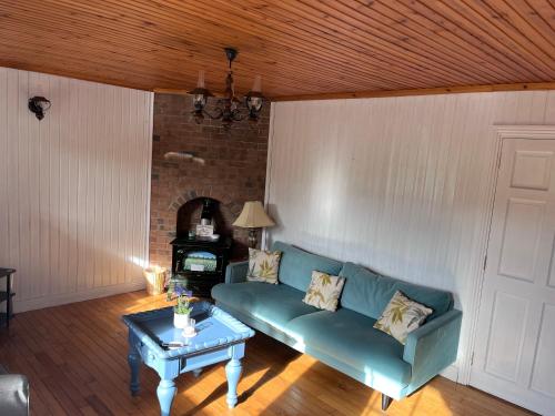 a living room with a green couch and a table at Cosy Lakeside Chalet With Option to add Private Hot Tub in Duneena