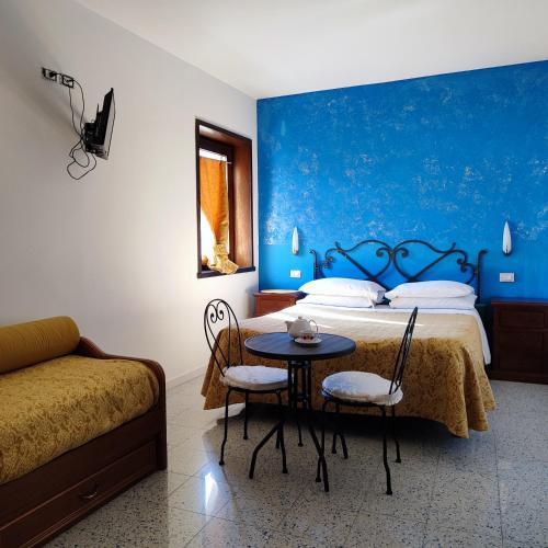 a bedroom with a bed and a table and a couch at B&B Home Holiday Villa delle Acacie agriturismo in Sala Consilina