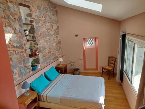 une chambre avec un lit et un mur en pierre dans l'établissement Le nid d'hirondelles, à Labeaume