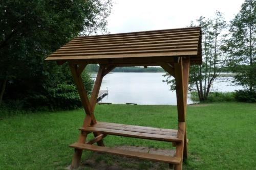 a wooden gazebo sitting in the grass next to a lake at Ferienhaus beim Stechlinsee in Stechlin