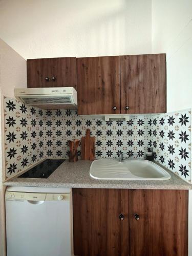 une cuisine avec un évier et des armoires en bois dans l'établissement Villa à 300m de la plage Richelieu, au Cap d'Agde