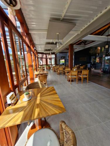 a dining room with tables and chairs and windows at Pousada Cantinho da Serra in Campos do Jordão