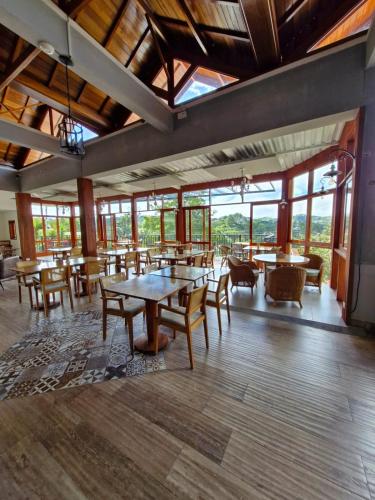 a large room with tables and chairs and windows at Pousada Cantinho da Serra in Campos do Jordão