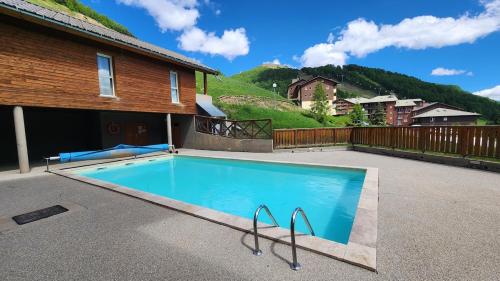 une piscine devant une maison dans l'établissement apartement 3 pieces avec piscine chauffée, à La Foux d'Allos