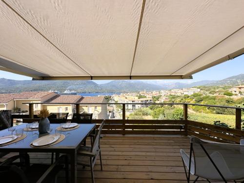 une terrasse en bois avec des tables et des chaises. dans l'établissement Superbe vue Mer et Montagne - T3 - 5mn des plages, à Propriano