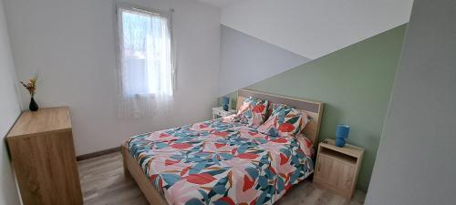 une chambre avec un lit avec une couette colorée dans l'établissement Maison 3 chambres, à Parentis-en-Born