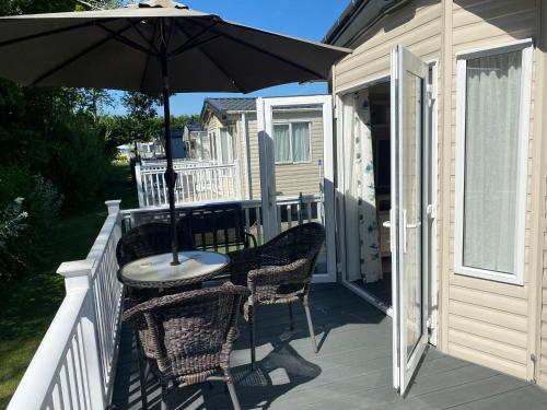 a patio with an umbrella and chairs on a deck at 2 Bed Static Caravan sleeps 6 Saxmunham in Saxmundham