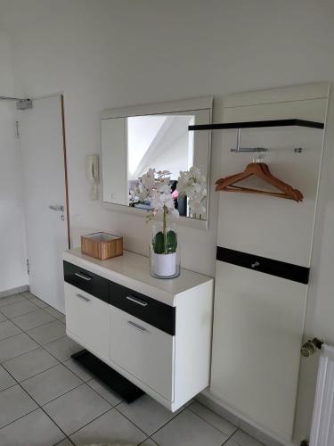 a white cabinet with a mirror and flowers on it at Studio No 3 in Heinsberg
