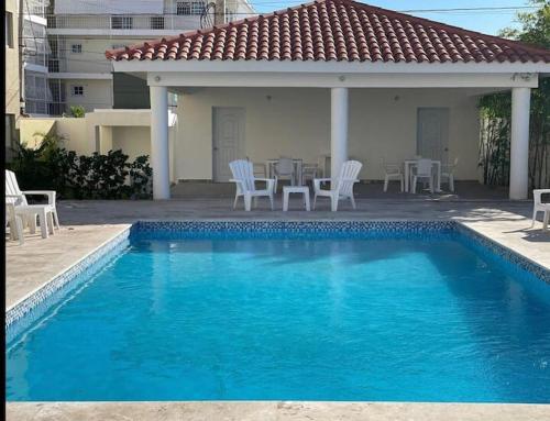 una piscina con sillas, una mesa y una casa en Beautiful Accommodation in La Romana Beach View, en La Romana