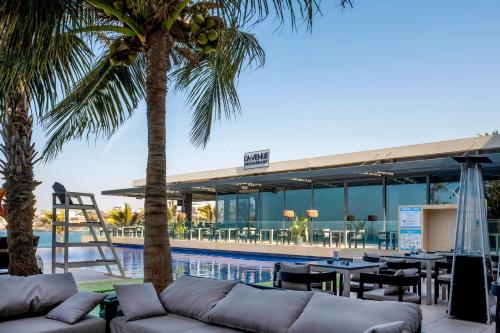达喀尔Noom Hotel Dakar Sea Plaza, a member of Radisson Individuals的客厅配有沙发,泳池旁种植了棕榈树