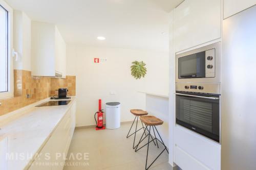 a white kitchen with a stove and a microwave at Modern 5BR Villa-Private Pool-Walk to Beach & Oura-10 Guests by Misha's Place in Albufeira