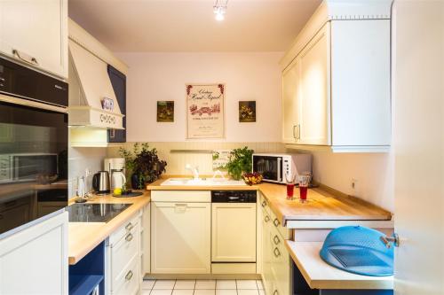 une cuisine avec des armoires blanches et des appareils électroménagers blancs dans l'établissement Le Daguerre, à Paris