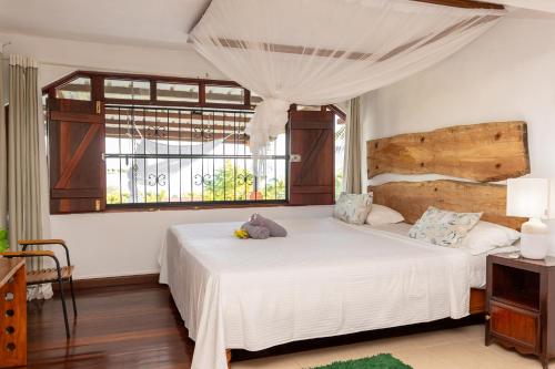 a bedroom with a large white bed with a window at Residence Ma Vie Là Ltee in Le Morne