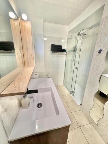 une salle de bain blanche avec un lavabo et une douche dans l'établissement Maison Emilie, à La Bréole