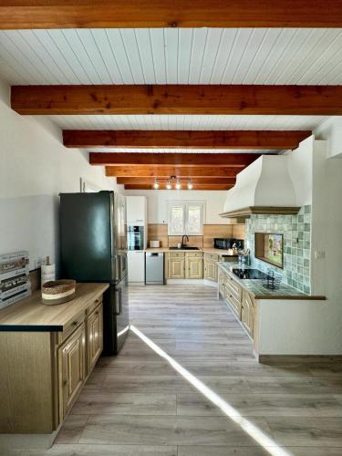 une grande cuisine avec des placards en bois et un réfrigérateur noir. dans l'établissement Maison Emilie, à La Bréole