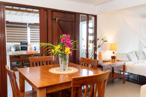 a dining room with a table with a vase of flowers on it at Residence Ma Vie Là Ltee in Le Morne