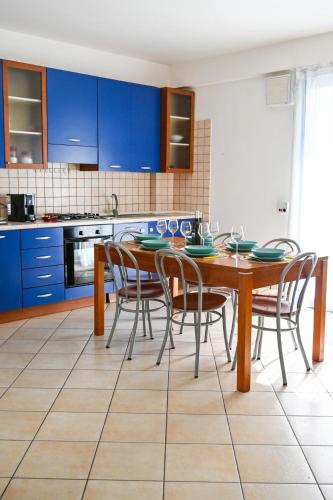 a kitchen with blue cabinets and a wooden table and chairs at casa azul netflix near the sea in Scoglitti