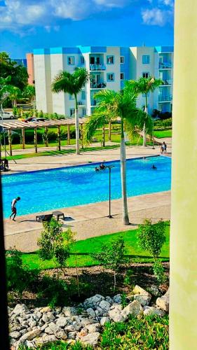a large swimming pool with palm trees in front of a building at Your Crissere Tropical Dream RD in Punta Cana