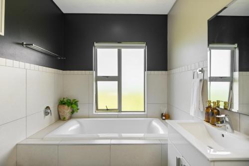 a white bathroom with a tub and a sink at 56 Zimbali Wedge in Ballito