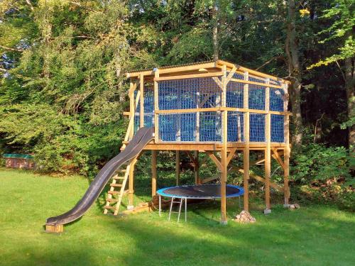 a tree house with a slide in the grass at Woody in Brösarp