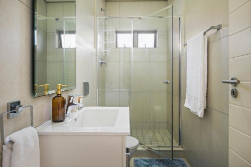 a bathroom with a sink and a glass shower at 56 Zimbali Wedge in Ballito