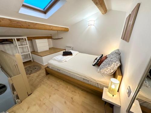 - une petite chambre avec un lit et une lucarne dans l'établissement Appartement avec terrasse arborée proche LOURMARIN, à Cadenet