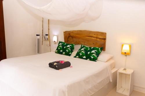 a bedroom with a white bed with green pillows at Residence Ma Vie Là Ltee in Le Morne