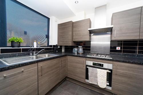 a kitchen with wooden cabinets and a sink at Specious modern 3-bed house near city centre in Reading