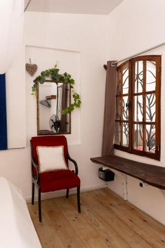 a red chair in a room with a mirror at Residence Ma Vie Là Ltee in Le Morne