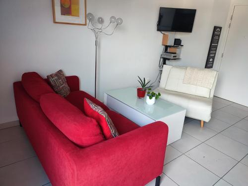 Una sala de estar con un sofá rojo y una mesa. en Location de charme T3 au 2e étage et dernier étage, en Cambo-les-Bains