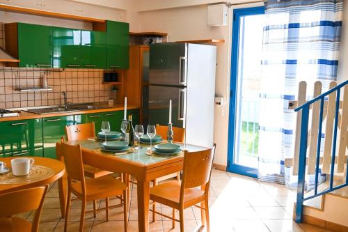 a kitchen with a table with chairs and a refrigerator at Casa Azul - Social Apartment - parcheggio, clima, 200mt dal mare in Scoglitti
